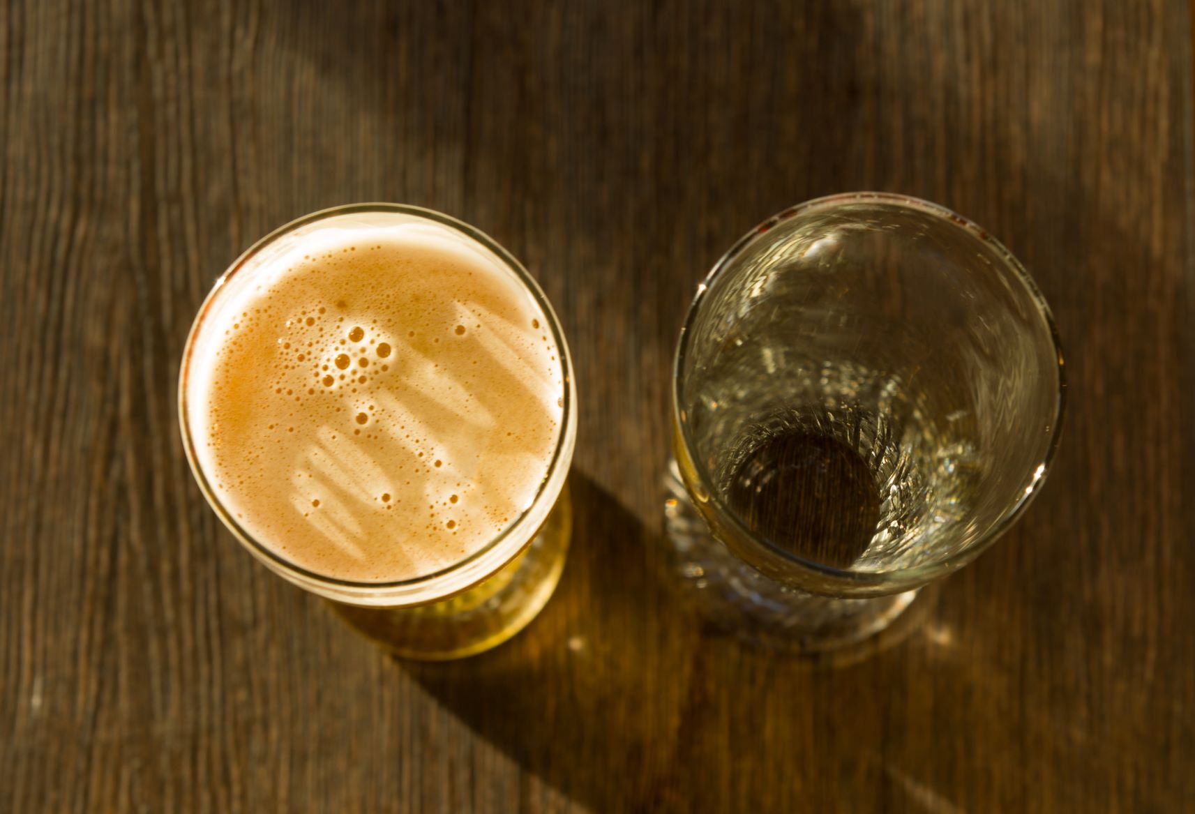 Full glass next to empty glass of brewed beverage 