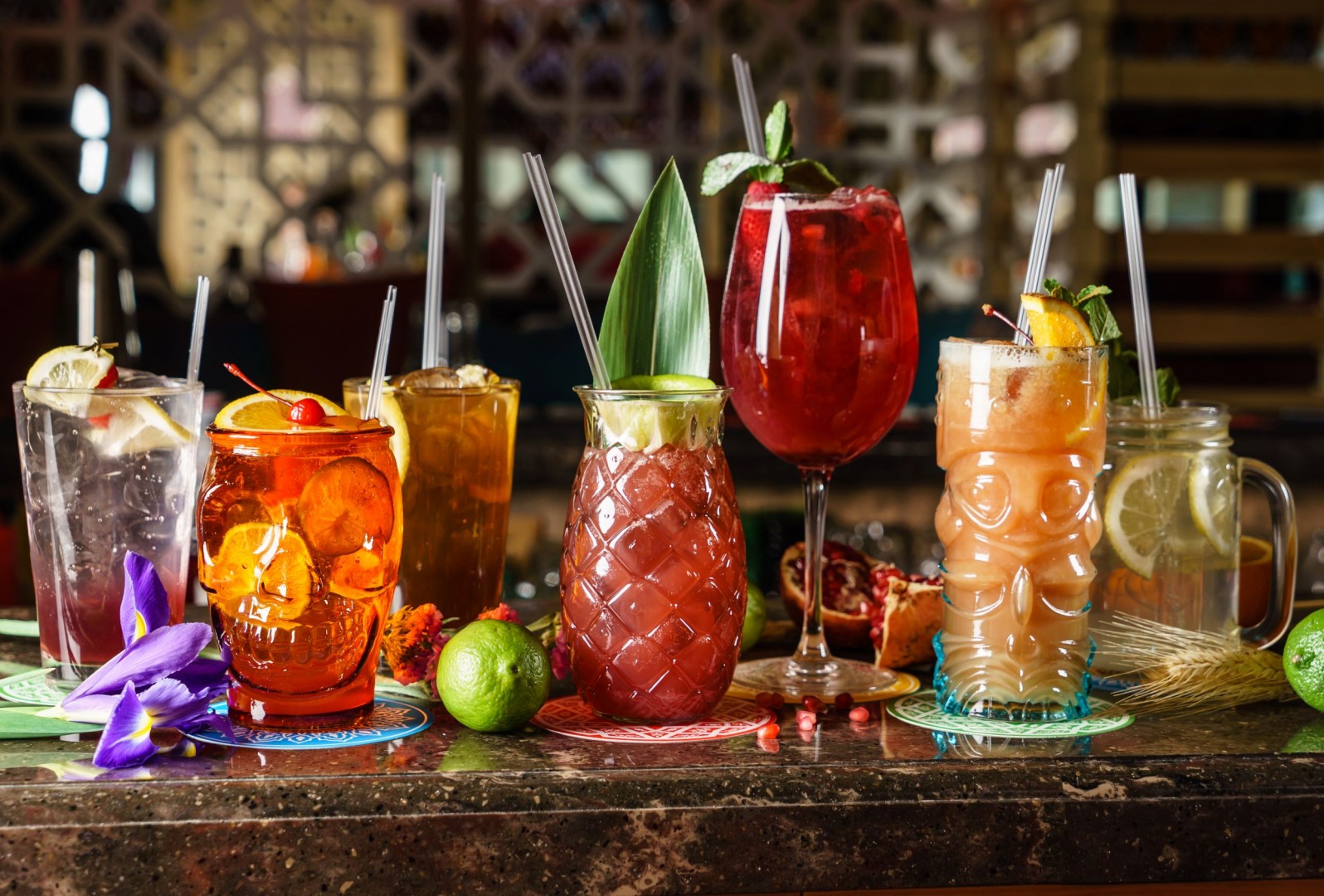 an array of cocktail-style drinks in different glass shapes, embellished with fruit slices and herbs